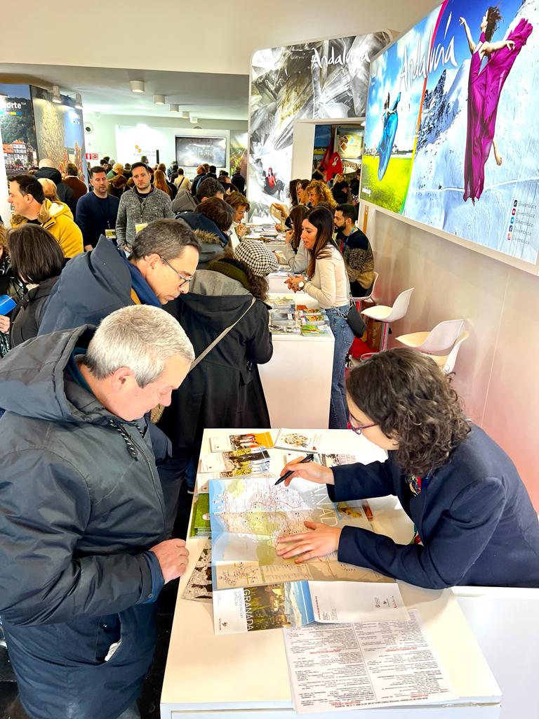 Varias personas miran folletos en el stand de Andalucía. NAVARTUR